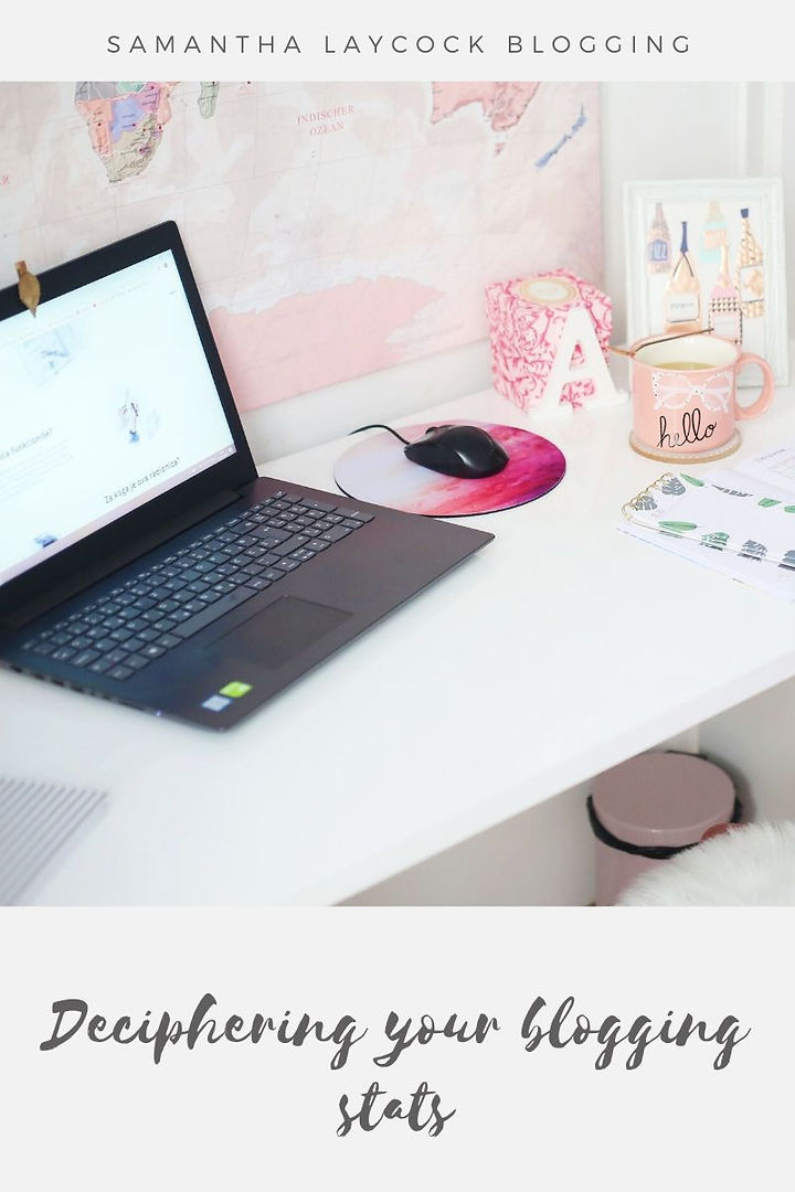 A desk with a laptop and mouse on it with a pink coffee mug. 